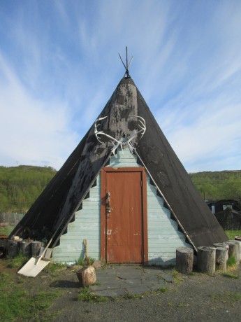 Sápmi Home, Titovka, Russia, from Thaw: An Arctic in Transition, 2014, Archival Inkjet Print, 24 x 20 inches, edition of 9. This shows a contemporary version of a traditional Sápmi home. The Sámi peoples, formerly known as Lapps, have traditionally inhabited the far northern regions of Sweden, Finland, and Norway, and the extreme northwest corner of Russia. This image was taken between Sputnik, Russia, a military town, and Murmansk, the largest town in the Arctic, with a population of about 330,000. Titovka, where the home is, is a very small hamlet along the side of the northernmost highway in the world, running about 100 miles between Kirkenes, Norway and Murmansk, Russia. Sápmi parliaments have been set up in the last 30 years in Sweden, Norway, and Finland to represent their interests in these nations. Russia has a non-governmental organization that advocates for its indigenous peoples.